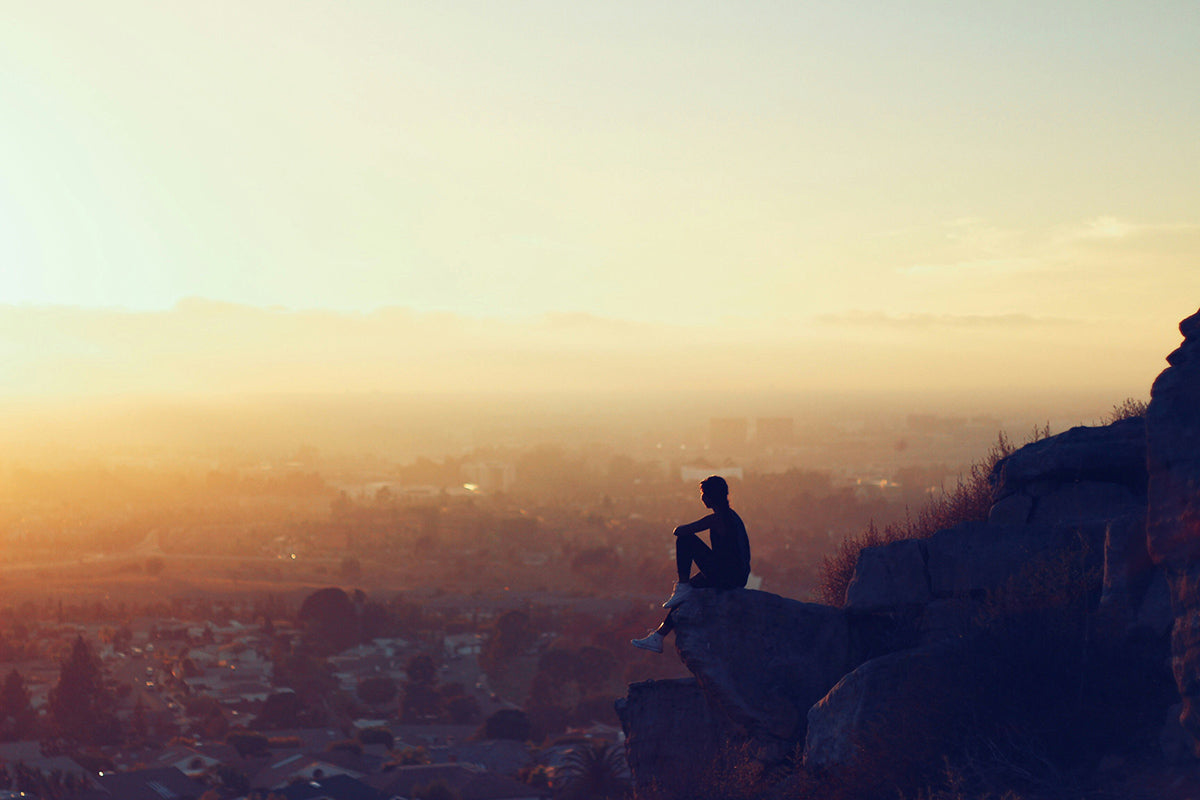 Man sitting on the edge of a cliff above the city
