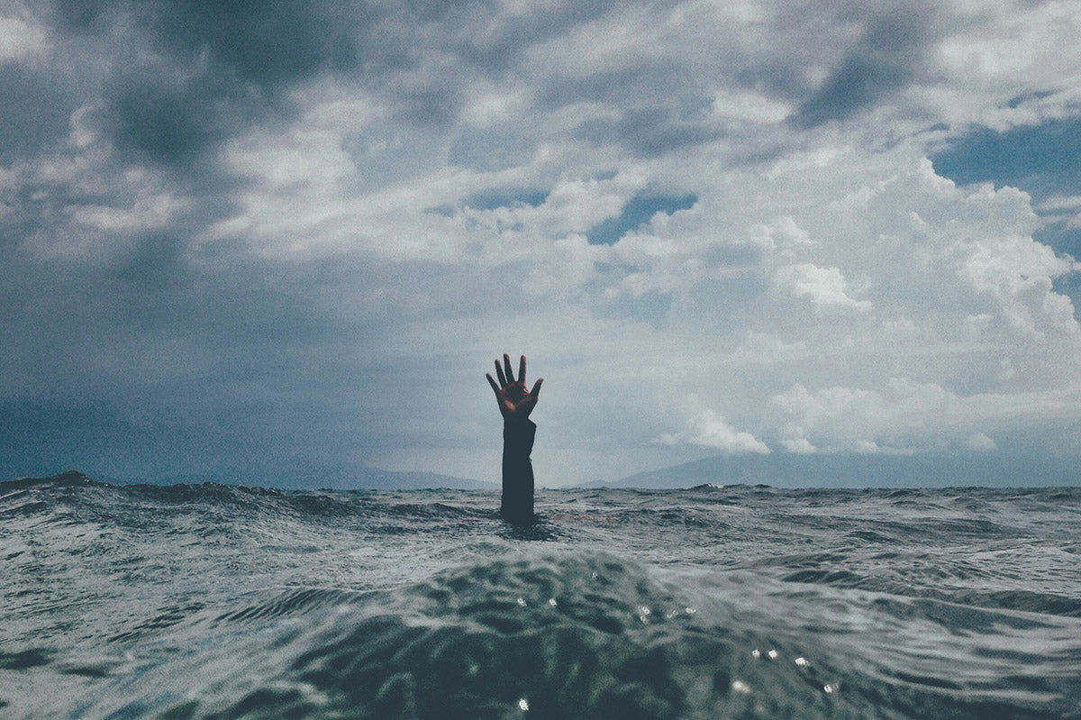 Hand in the sea water asking for help