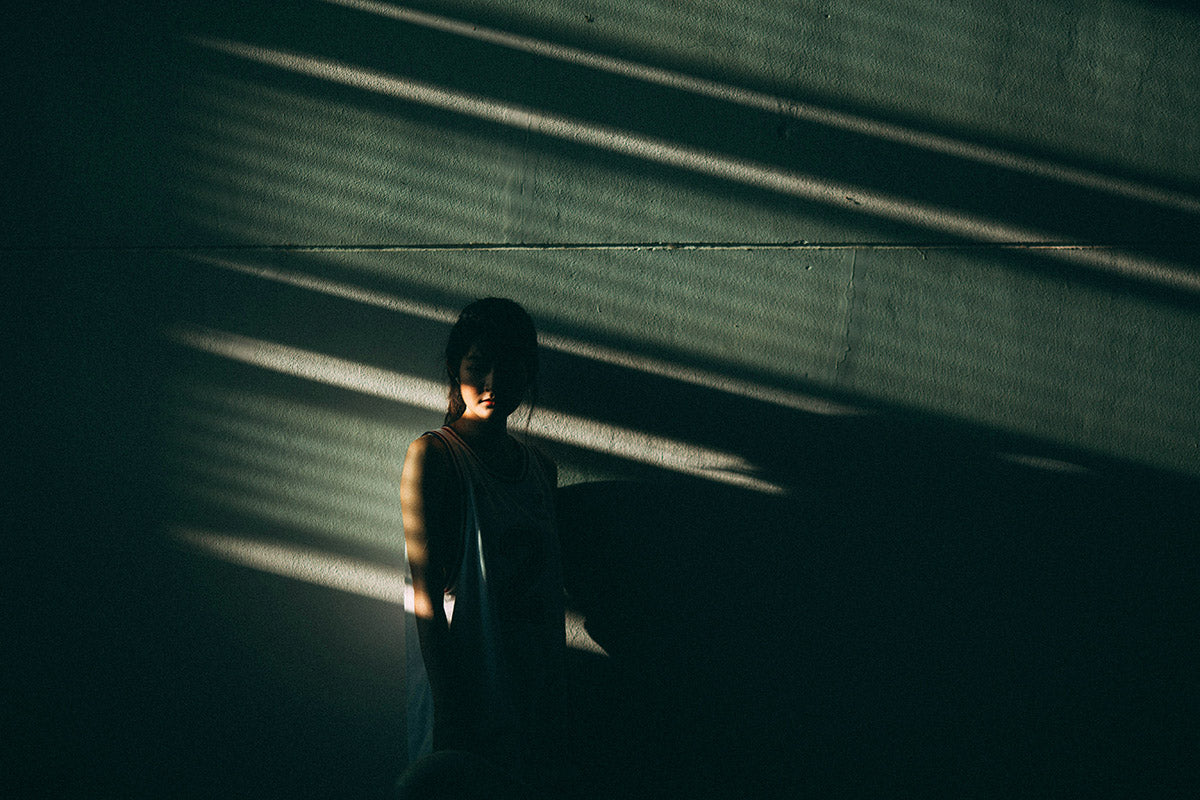 Sunlight filters and illuminates a woman who looks sad